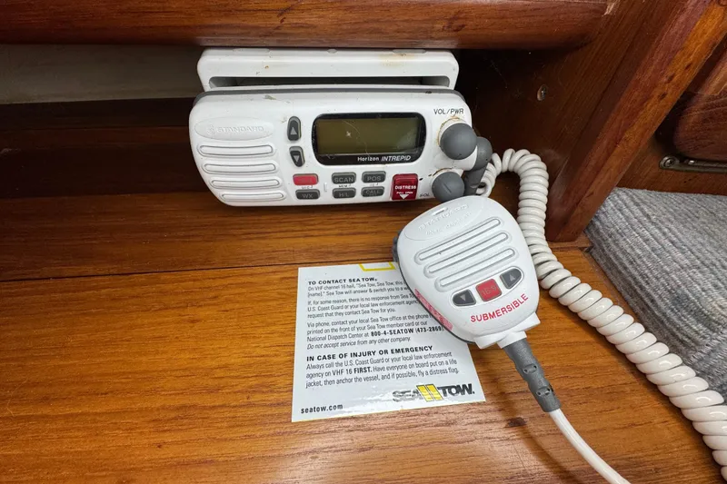 Slide: The Image of VHF marine radio on 1992 Hunter 33.5 sailboat, with microphone and emergency instructions. - 61