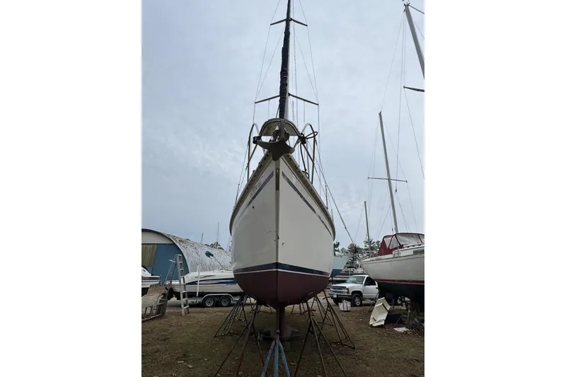 Slide: The Image of 1992 Hunter 33.5 sailboat on land, supported by stands, with overcast sky. - 8
