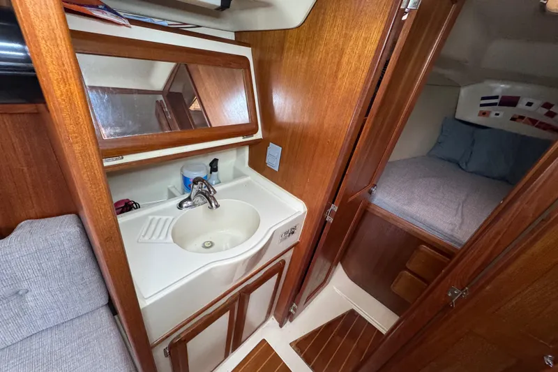 Slide: The Image of 1992 Hunter 33.5 yacht interior with sink, mirror, and cozy sleeping area. - 81