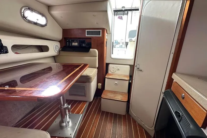 Slide: The Image of 2004 Pursuit 3100 Offshore cabin interior with wood accents and seating area. - 3