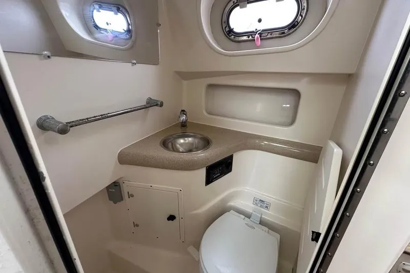 Slide: The Image of 2004 Pursuit 3100 Offshore boat bathroom with sink, toilet, and porthole windows. - 4