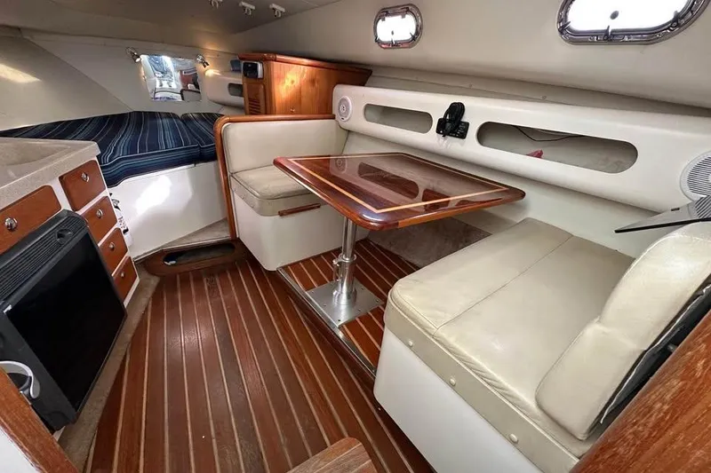 Slide: The Image of 2004 Pursuit 3100 Offshore cabin interior with wood flooring, seating, and table. - 5