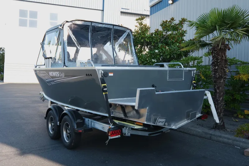 Slide: The Image of 2025 Hewescraft 190 SeaRunner ET boat on trailer, parked near palm trees. - 4