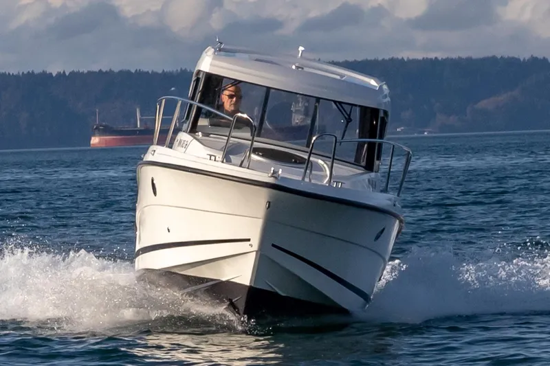 Slide: The Image of 2023 Parker Poland Skamander boat cruising on open water, with a distant ship in the background. - 3