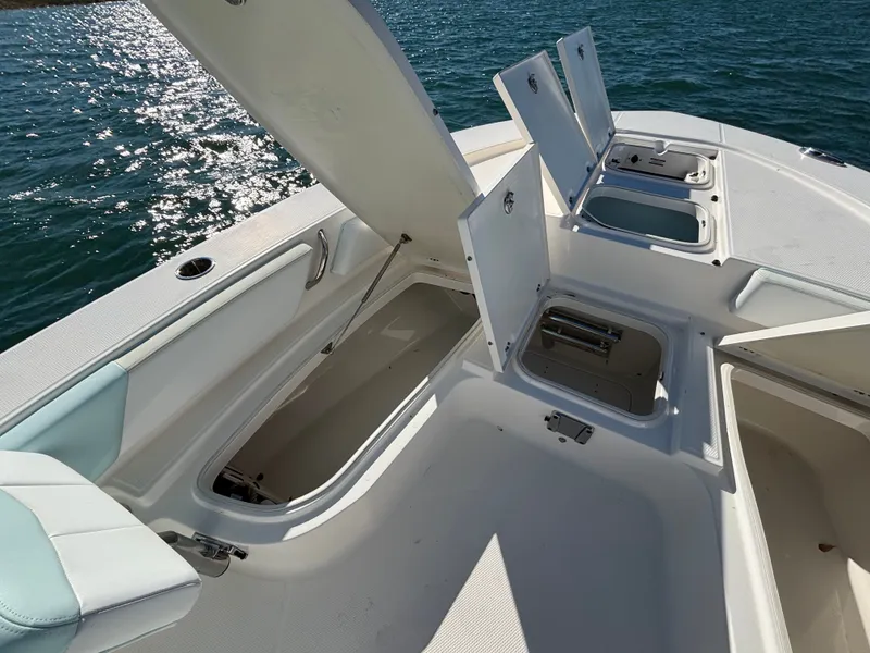 Slide: The Image of 2018 Robalo 246 Cayman with open storage compartments on water. - 48