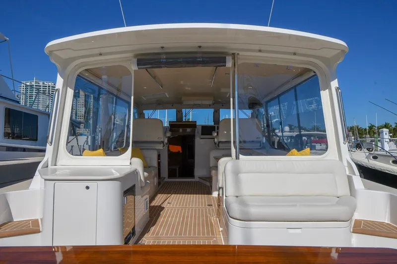 Slide: The Image of 2018 MJM 50z yacht interior with white seating and wooden flooring, docked under clear blue sky. - 13