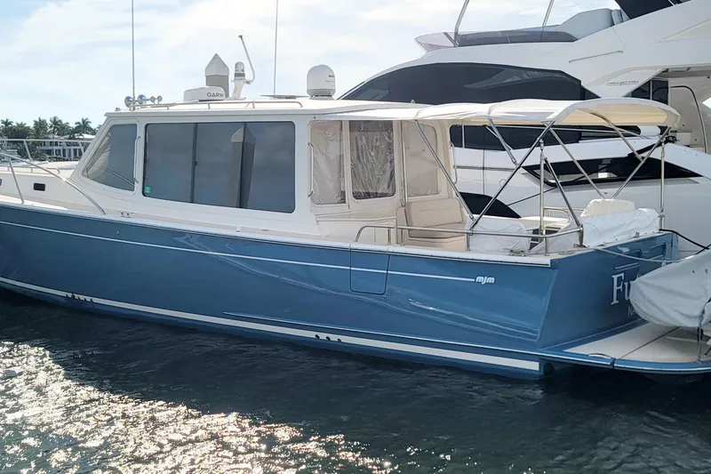 Slide: The Image of 2018 MJM 50z yacht docked, featuring sleek blue hull and spacious deck. - 4