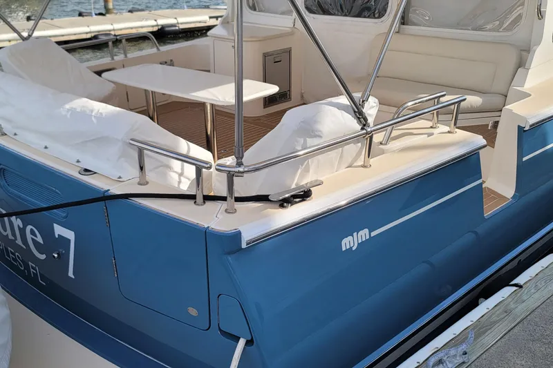 Slide: The Image of 2018 MJM 50z boat with blue exterior, docked, featuring a spacious seating area. - 7