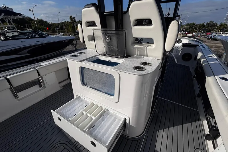 Slide: The Image of 2026 Tidewater 3100 Carolina Bay boat interior with seating and storage, under a clear blue sky. - 20