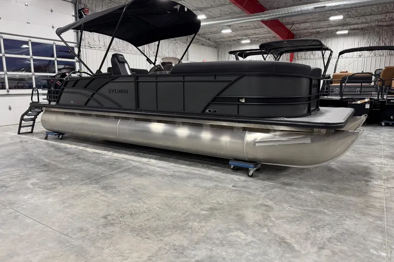 The Image of 2026 Sylvan X 5 pontoon boat in a showroom, featuring sleek black design and modern amenities. - 1