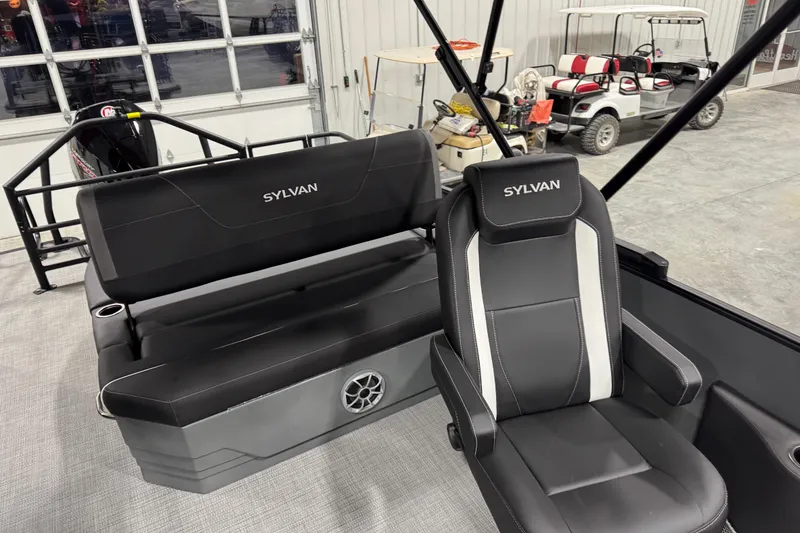 Slide: The Image of 2026 Sylvan X 5 boat interior with black seating and steering chair in a garage setting. - 11