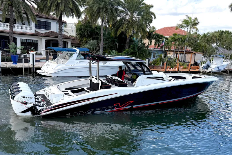 The Image of 2019 MTI V42 boat docked near waterfront homes with palm trees. - 1