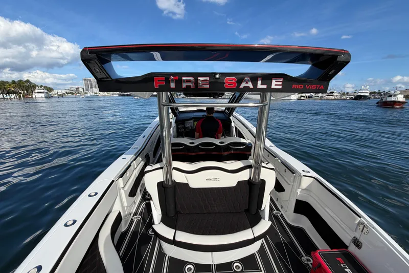Slide: The Image of 2019 MTI V42 boat on water, "Fire Sale" sign, clear sky, waterfront view. - 13