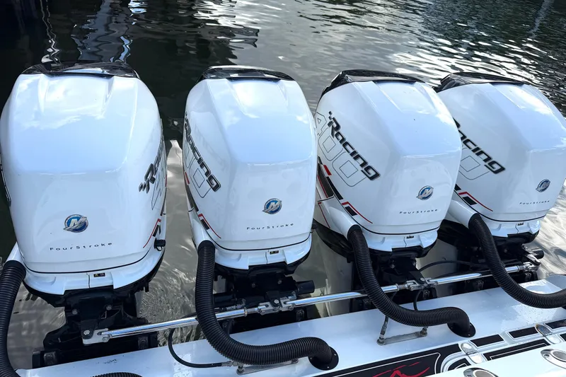 Slide: The Image of Four powerful outboard motors on a 2019 MTI V42 boat, reflecting on water. - 14