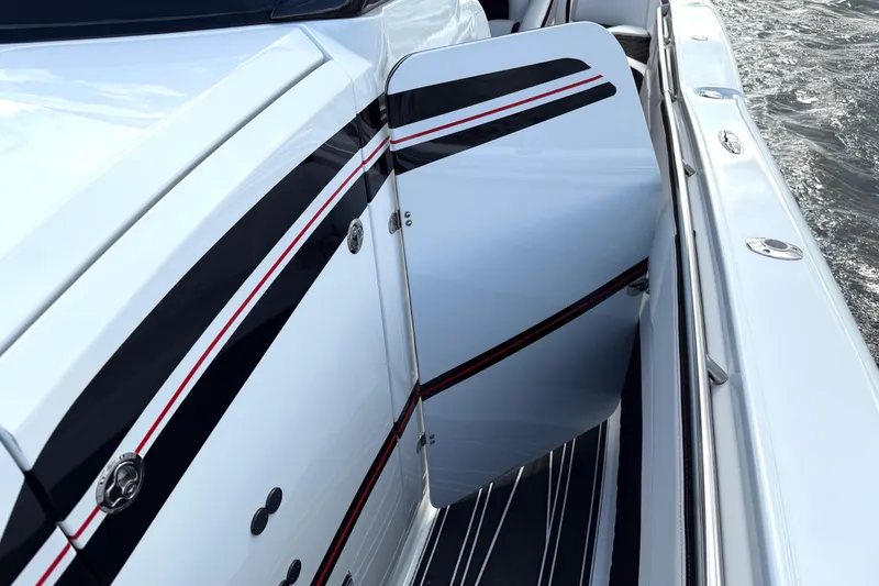 Slide: The Image of 2019 MTI V42 boat with open side door, featuring sleek black and red stripes. - 26