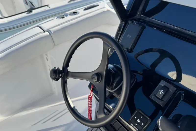Slide: The Image of Steering wheel of 2026 Tidewater 232 LXF boat, featuring sleek black dashboard design. - 15