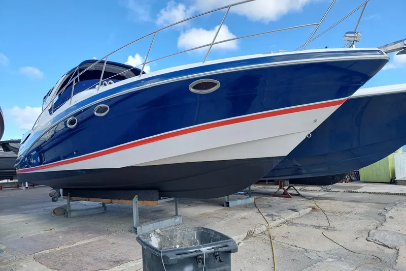 Slide: The Image of 2005 Four Winns 348 Vista boat on dry dock, blue hull, white and red accents. - 112
