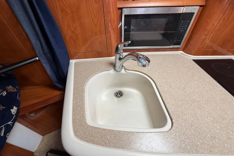 Slide: The Image of 2005 Four Winns 348 Vista kitchen sink with faucet and microwave in wooden interior. - 58