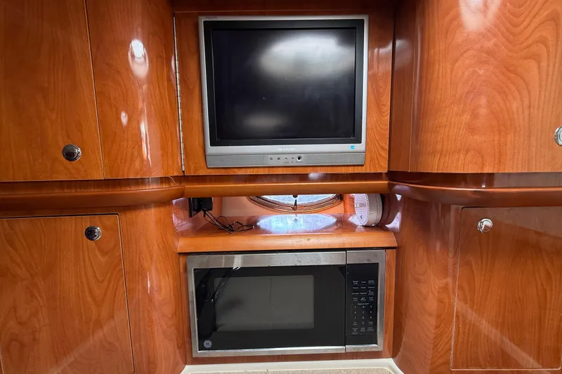 Slide: The Image of 2005 Four Winns 348 Vista interior with TV and microwave, featuring polished wood cabinetry. - 59