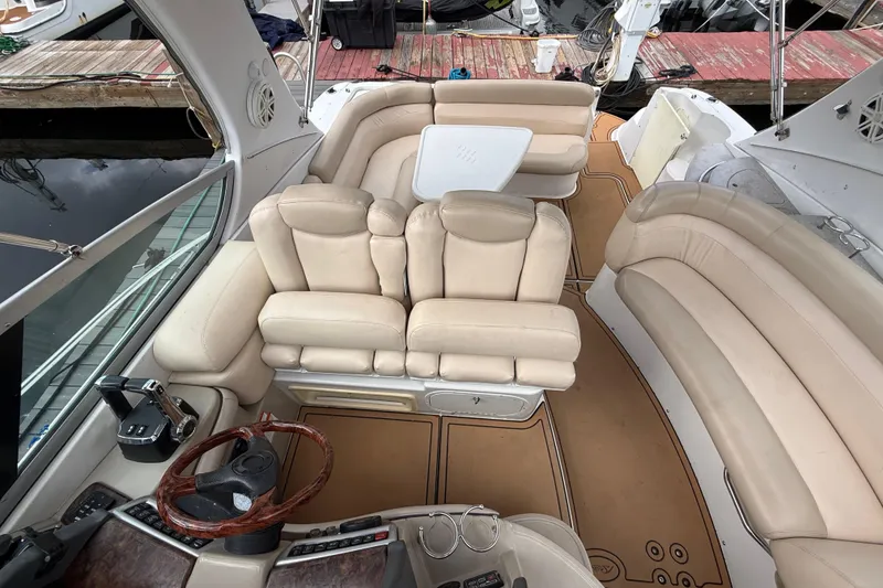 Slide: The Image of 2005 Four Winns 348 Vista boat interior with beige seating and wooden steering wheel. - 95