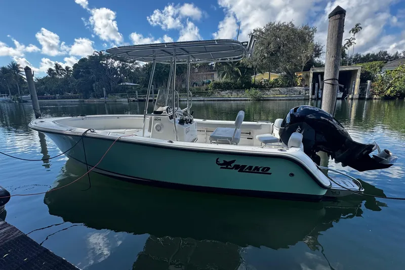 Slide: The Image of 2018 Mako 204 Center Console boat docked on a calm waterway under a blue sky. - 0