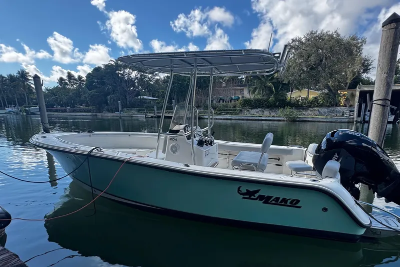 Slide: The Image of 2018 Mako 204 Center Console boat docked on a calm waterway under a blue sky. - 1