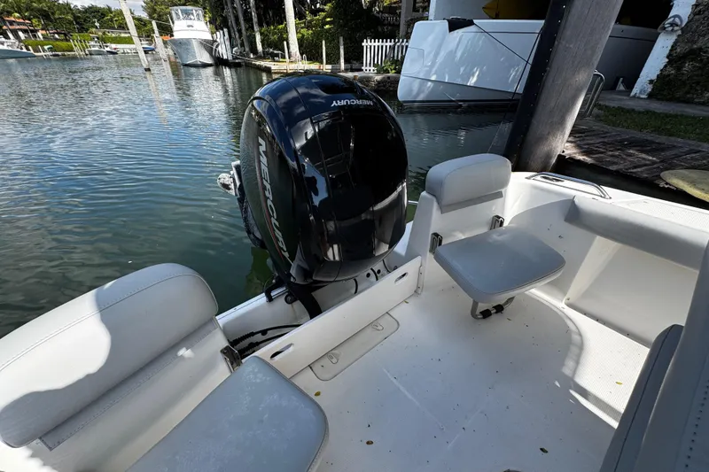 Slide: The Image of 2018 Mako 204 Center Console boat with Mercury engine, docked in a serene marina. - 24