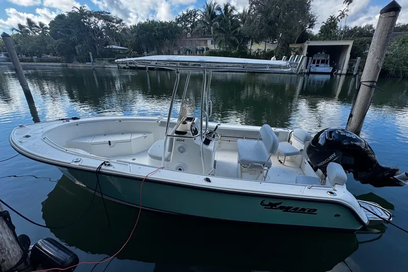 Slide: The Image of 2018 Mako 204 Center Console boat docked on calm water, surrounded by lush greenery. - 3