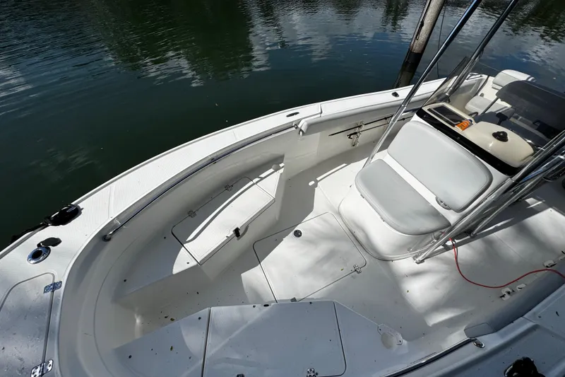 Slide: The Image of 2018 Mako 204 Center Console boat interior with seating and storage, docked on calm water. - 7