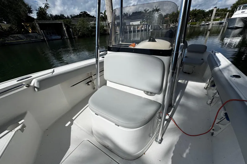 Slide: The Image of 2018 Mako 204 Center Console boat interior with seating and console, docked by a serene waterfront. - 8
