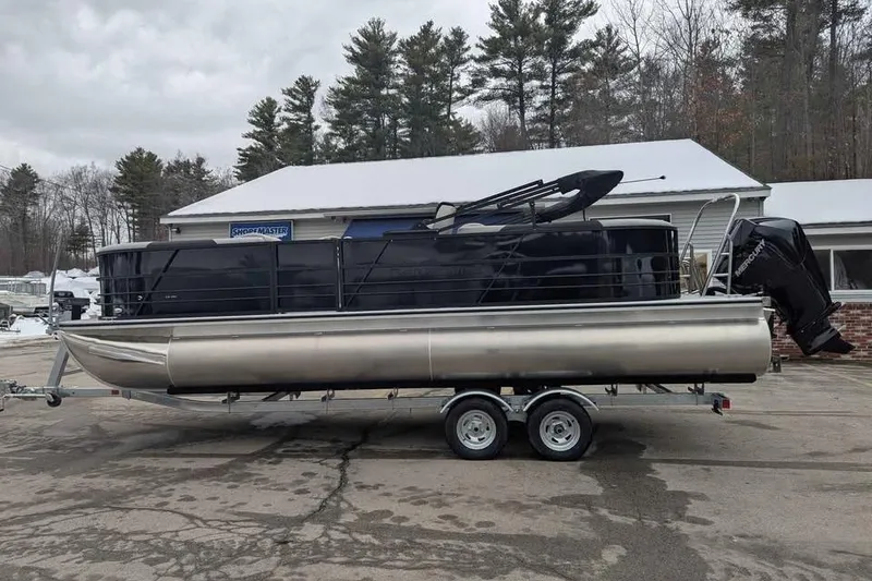 Slide: The Image of 2026 Berkshire 24RFX LE pontoon boat on trailer, parked outdoors near trees. - 5