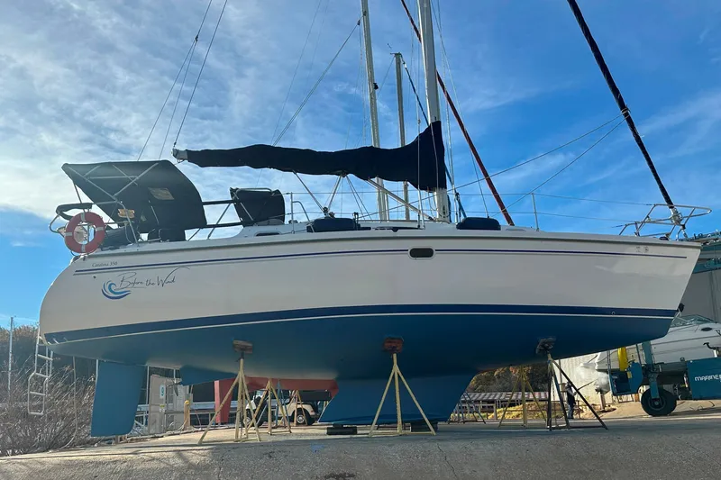The Image of 2003 Catalina 350 sailboat on stands, blue and white hull, clear sky background. - 0