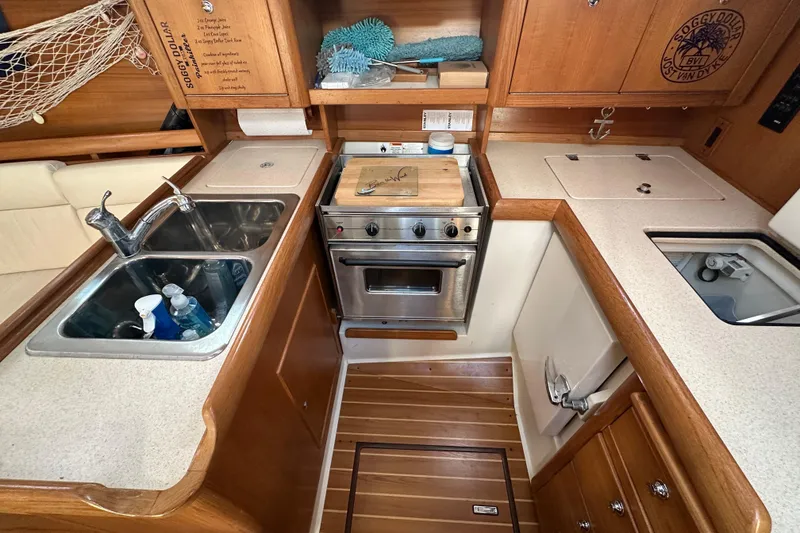 Slide: The Image of Catalina 350 yacht kitchen interior, featuring a sink, stove, and wooden cabinetry, 2003 model. - 35