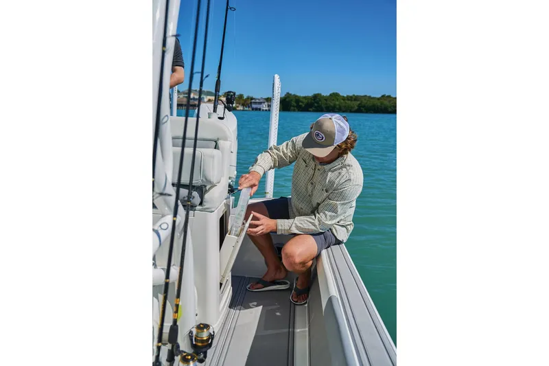 Slide: The Image of Man organizing fishing gear on a 2026 Mako 24 APEX boat in sunny waters. - 67