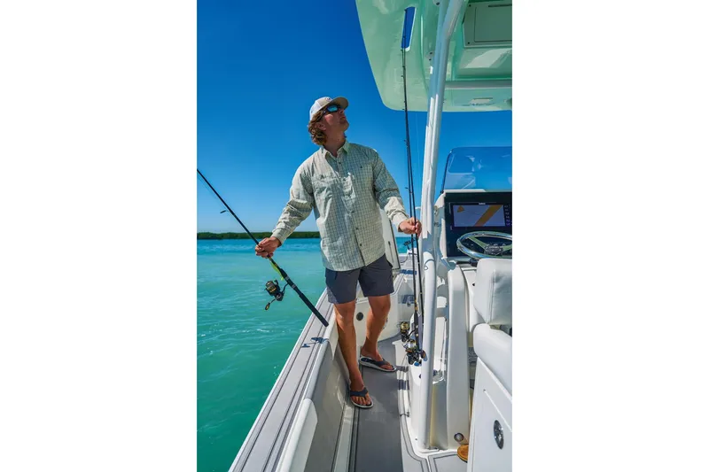 Slide: The Image of Man fishing on a 2026 Mako 24 APEX boat under clear blue skies. - 61