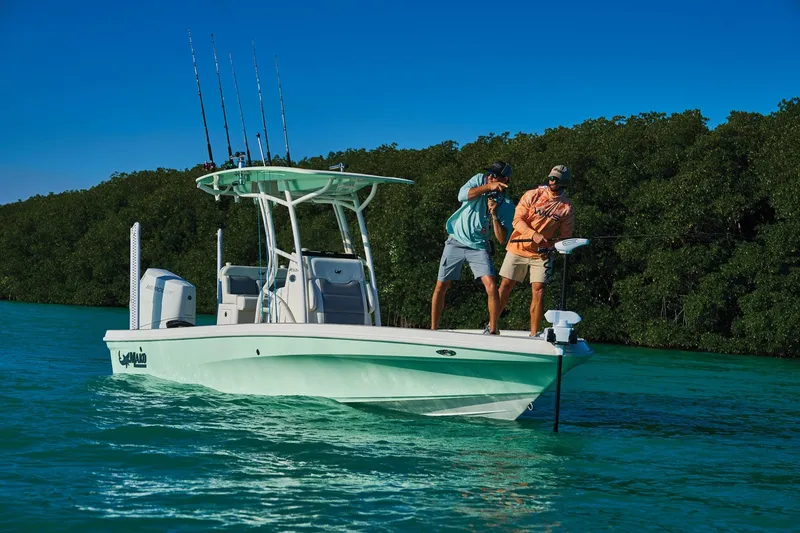 Slide: The Image of Two people fishing on a 2026 Mako 24 APEX boat in clear blue water. - 58