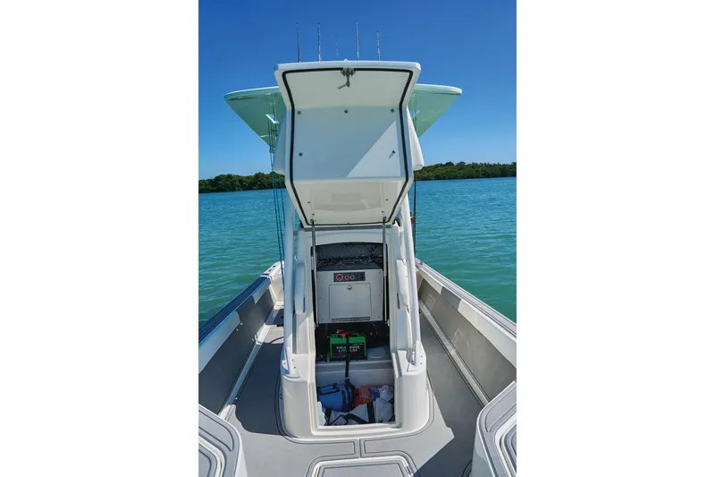 Slide: The Image of 2026 Mako 24 APEX boat with open storage compartment on calm water. - 66