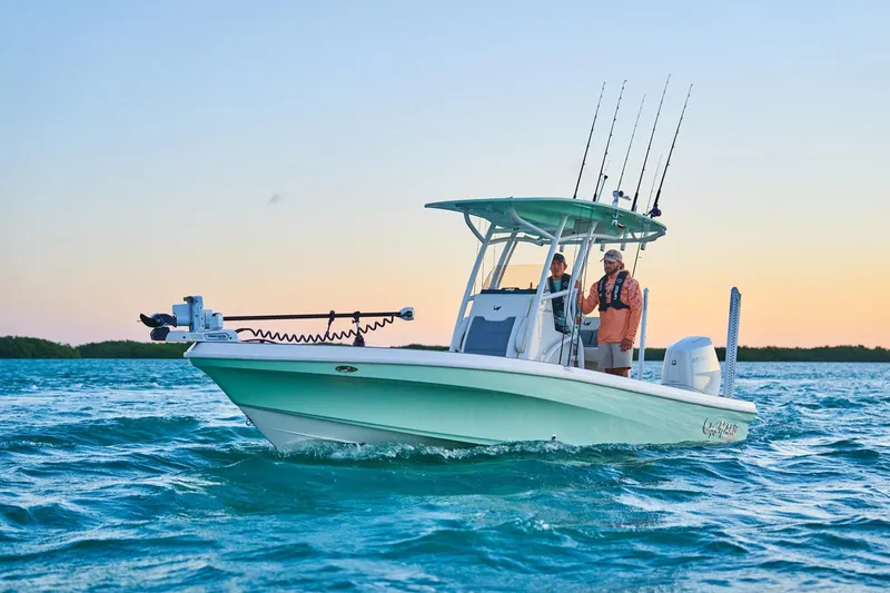 Slide: The Image of 2026 Mako 24 APEX boat cruising on ocean at sunset with fishing gear. - 55