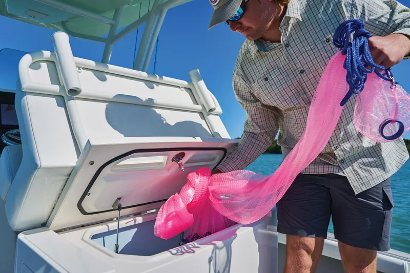 Slide: The Image of Man handling fishing net on 2026 Mako 24 APEX boat, open storage compartment. - 73