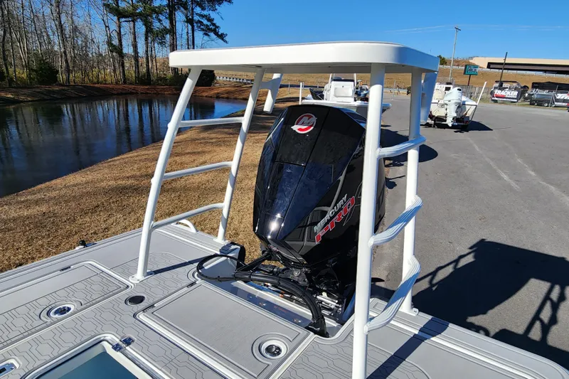 Slide: The Image of 2026 Mako 18 Pro Skiff with Mercury Pro engine, parked near a serene lake. - 3