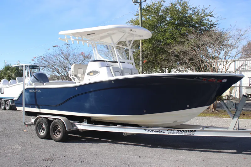 Slide: The Image of 2021 Sea Fox 249 Avenger boat on trailer, blue hull, parked outdoors. - 2