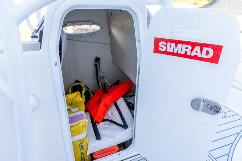 Slide: The Image of Storage compartment on 2017 Sea Pro 248 Bay boat with safety gear and Simrad label. - 14
