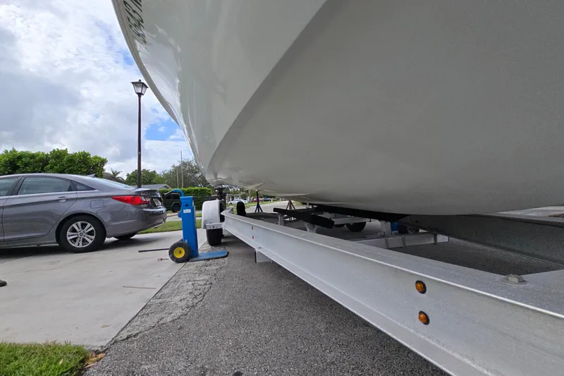 Slide: The Image of 2007 Yellowfin 24 Bay boat on trailer, parked beside a car on a driveway. - 14