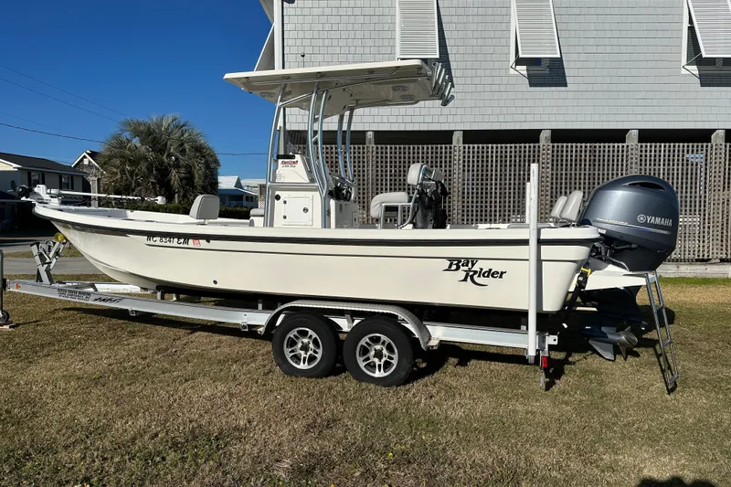 Slide: The Image of 2020 Bay Rider 239 Bay boat on trailer, parked outdoors with Yamaha outboard motor. - 2