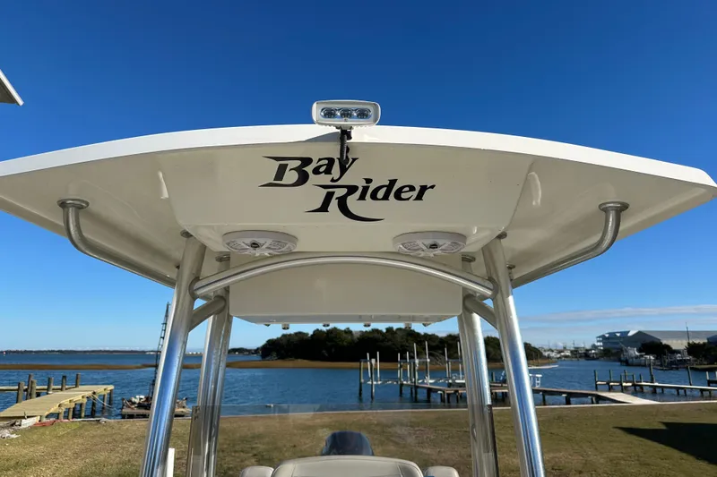 Slide: The Image of Bay Rider 239 Bay 2020 boat with T-top, docked by a scenic waterfront. - 27