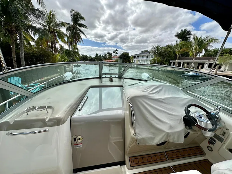 Slide: The Image of 2008 Sea Ray 340 Sundancer boat cockpit with covered steering wheel, docked near palm trees. - 17