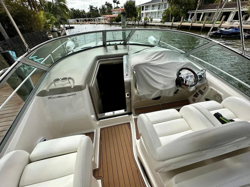 Slide: The Image of 2008 Sea Ray 340 Sundancer cockpit with white seating and covered steering wheel, dockside view. - 26