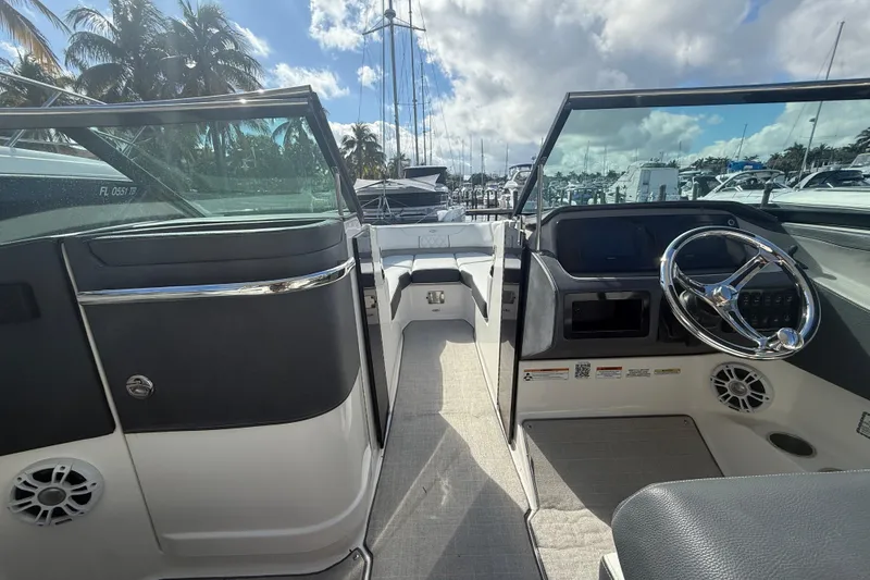Slide: The Image of 2022 Regal LX6 boat interior with steering wheel, docked under a partly cloudy sky. - 5