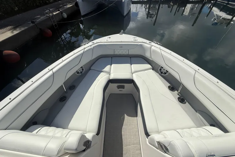 Slide: The Image of 2022 Regal LX6 boat interior with white seating and cup holders in a marina. - 6