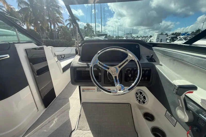 Slide: The Image of 2022 Regal LX6 boat cockpit with steering wheel, dashboard, and controls under a sunny sky. - 7
